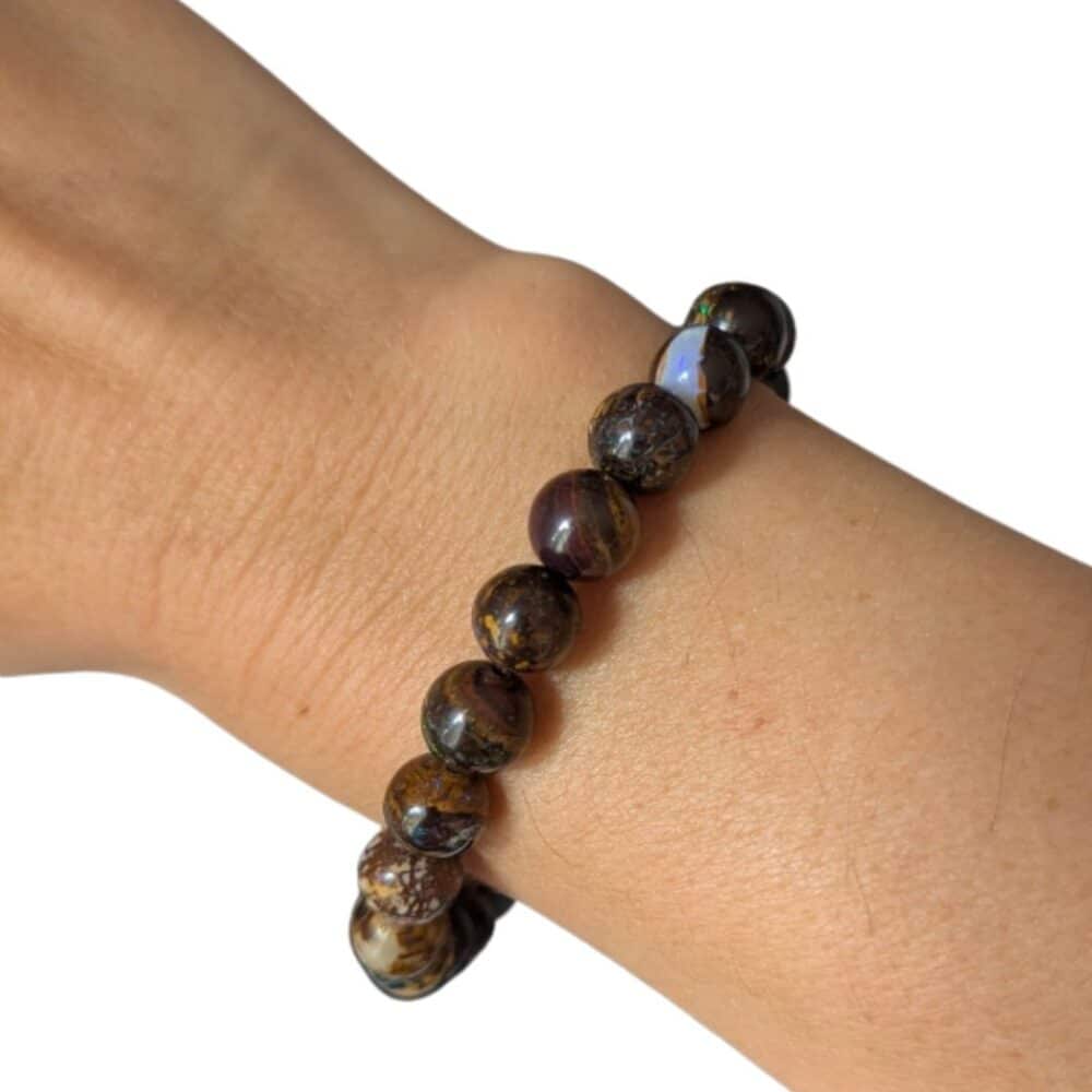 Bracelet en opale Boulder naturelle 8 mm porté au poignet, un bijou haut de gamme aux reflets uniques favorisant la créativité, la confiance en soi et l'intuition.