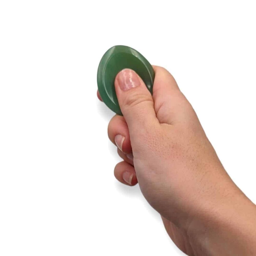 Main utilisant un worry stone en aventurine verte en frottant la pierre avec le pouce