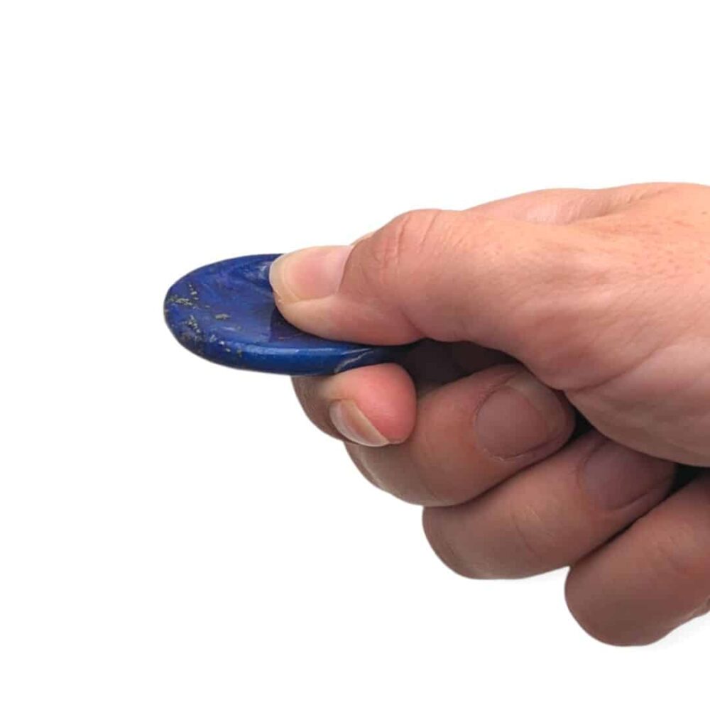 Main utilisant un worry stone en lapis-lazuli en frottant la pierre avec le pouce