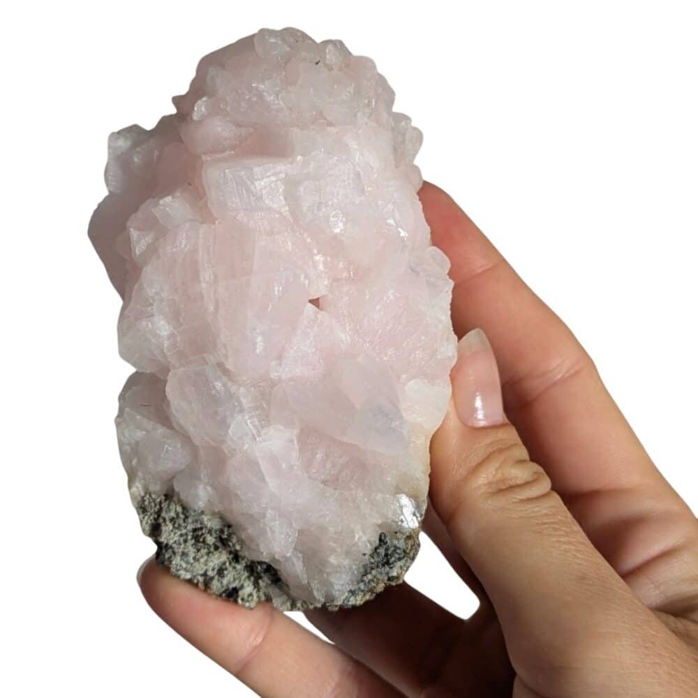 Manganocalcite brute naturelle tenue en main, une pierre aux délicates nuances roses reconnue pour apporter douceur, sérénité et réconfort émotionnel.