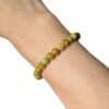 Bracelet en opale verte 6 mm porté au poignet, un bijou élégant en pierre naturelle pour retrouver l'harmonie, l'optimisme et l'équilibre émotionnel.